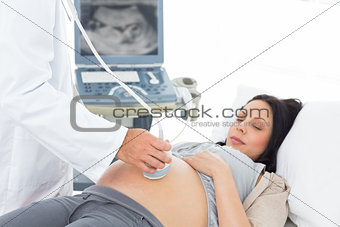 Male doctor performing ultrasound on pregnant woman