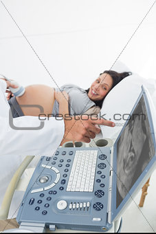 Doctor showing ultrasound monitor to pregnant woman