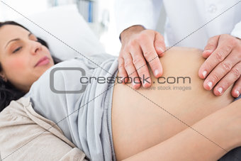 Doctor touching stomach of pregnant woman