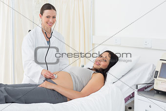 Happy female doctor checking pregnant woman