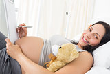 Portrait of pregnant woman writing on clipboard