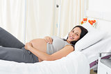 Smiling pregnant woman lying in hospital