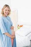 Happy pregnant woman wearing hospital gown