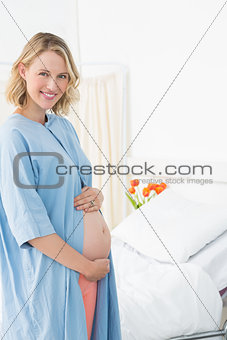 Happy pregnant woman wearing hospital gown