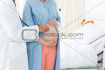 Doctor checking pregnant woman with stethoscope