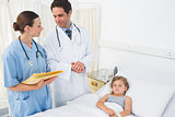 Doctors discussing while attending sick girl