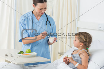 Doctor feeding meal to sick girl