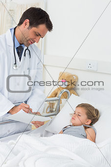 Doctor writing on clipboard while attending ill girl