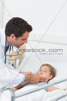 Doctor examining thyroid glands of sick girl