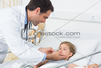 Smiling doctor checking thyroid glands of ill girl