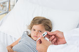 Doctor holding thermometer with girl in hospital