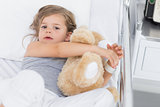 Cute girl hugging teddy bear in hospital bed