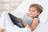 Sick girl with digital tablet in hospital bed