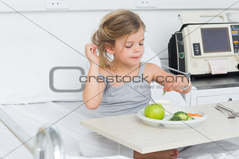 Girl eating healthy food in hospital bed