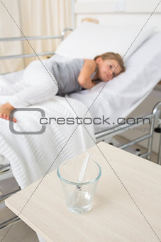 Syringe in glass with girl resting in hospital