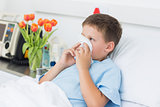 Boy blowing nose into tissue in hospital