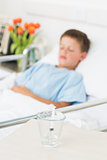 Syringe in glass with boy resting in hospital ward