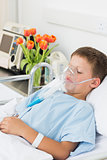 Boy wearing oxygen mask in hospital bed
