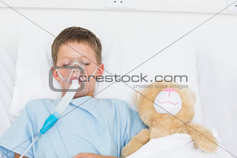 Boy wearing oxygen mask sleeping beside stuffed toy