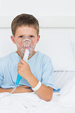Boy wearing oxygen mask in hospital ward