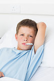 Boy with thermometer in mouth in ward