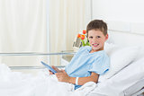 Boy using digital tablet in hospital bed