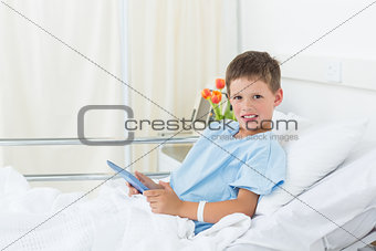Boy using digital tablet in hospital bed