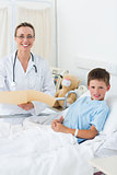 Female doctor with boy in hospital bed