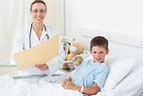 Female doctor with boy in hospital bed