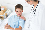 Doctor comforting sick boy in ward