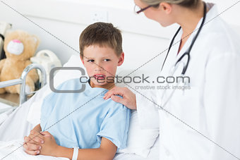Doctor comforting sick boy in ward