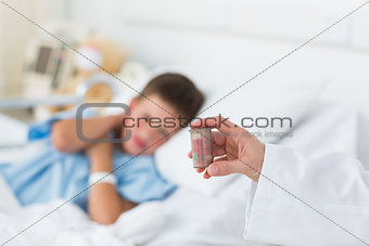 Doctor holding pill bottle with boy in hospital