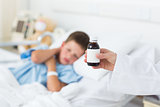 Doctor holding cough syrup with boy in hospital