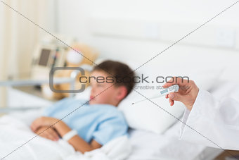 Doctor holding thermometer with boy in hospital