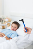 Doctor holding otoscope with boy in hospital