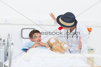 Doctor entertaining sick boy in hospital bed