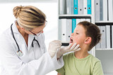 Doctor looking into the mouth of boy