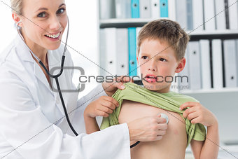 Confident doctor examining boy with stethoscope