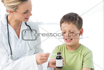 Pediatrician giving little boy syrup
