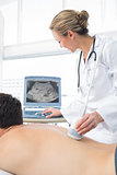 Doctor using sonogram on back of male patient