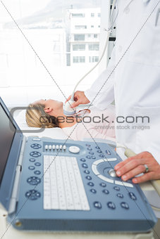 Doctor performing ultrasound scan on neck of patient