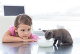 Girl looking at kitten drinking milk from bowl