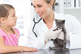 Veterinarian examining kitten with girl