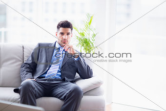 Serious businessman sitting on the sofa looking at camera
