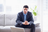 Happy businessman sitting on the sofa looking at camera