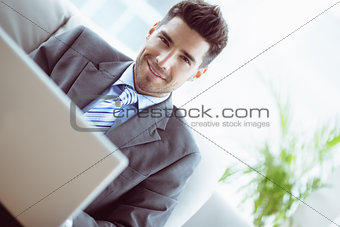 Handsome businessman sitting on couch using his laptop