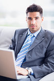 Attractive businessman sitting on couch using his laptop