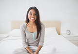 Pretty girl sitting on bed smiling at camera