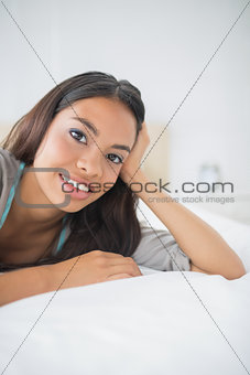 Pretty young girl lying on bed smiling at camera