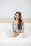 Young girl sitting on bed smiling at camera